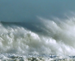 Photograph showing the sea spray above some waves.